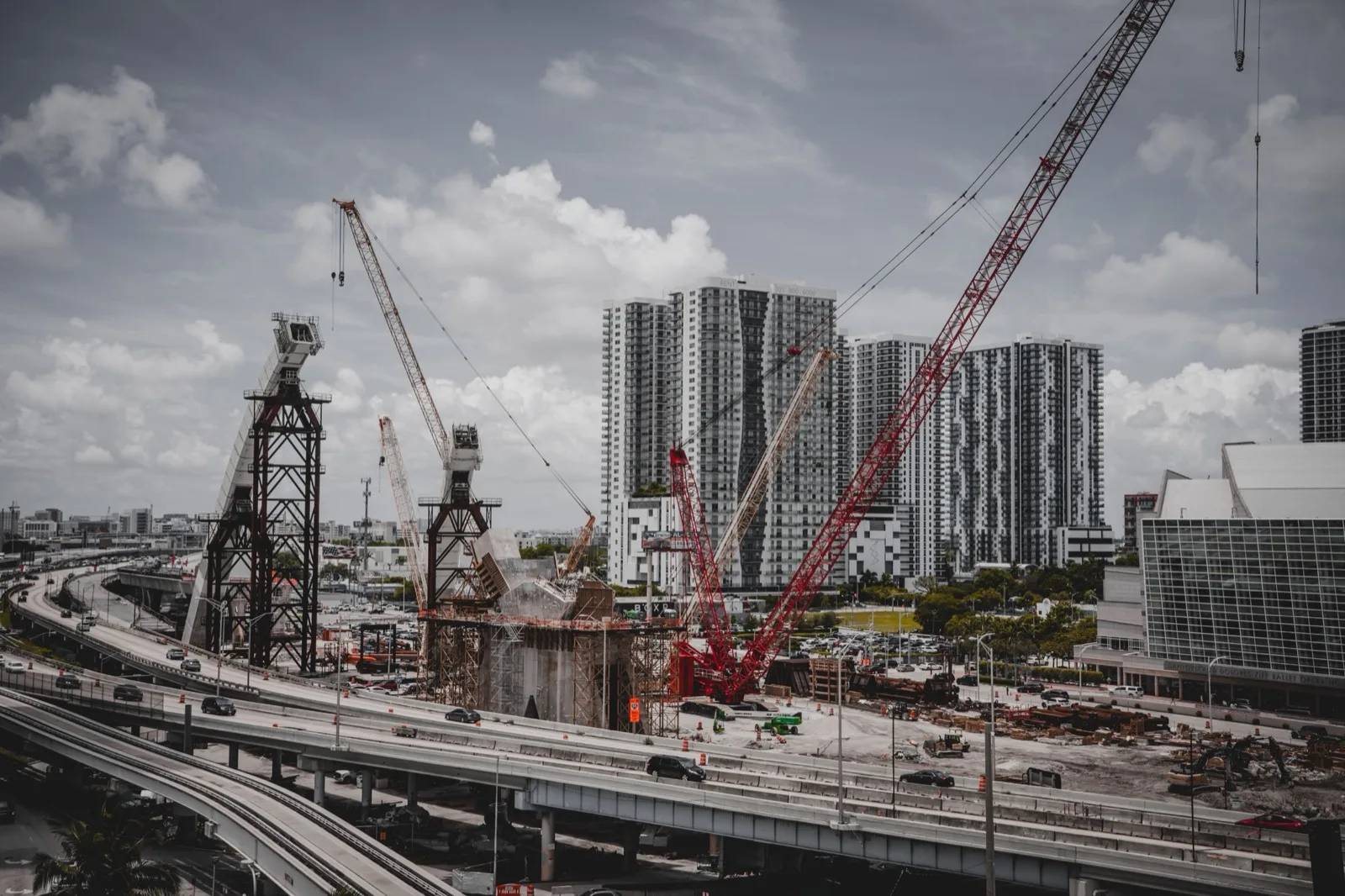 Crawler cranes and bridge piers on an infrastructure jobsite, towers in the distance