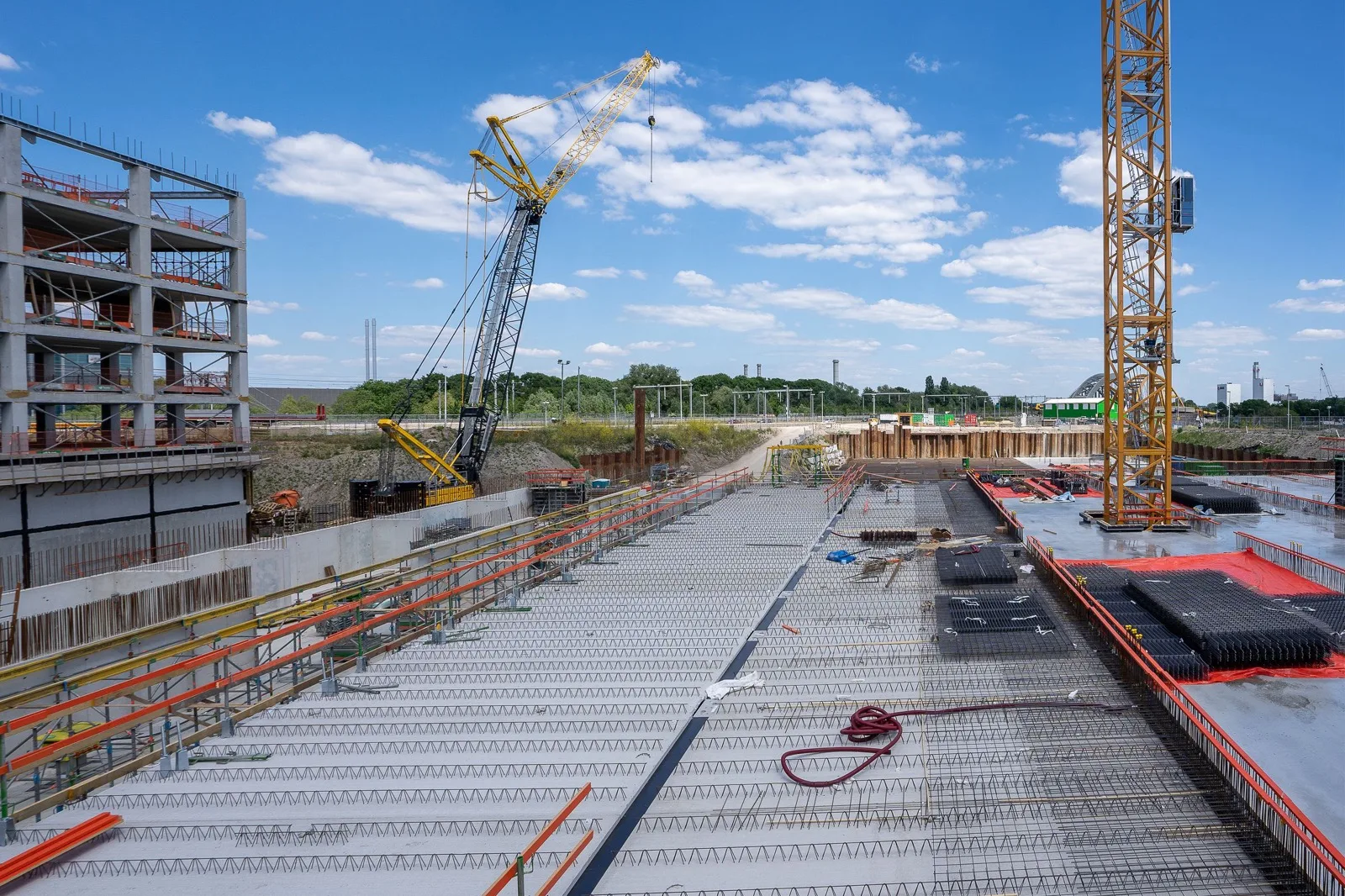 Concrete deck with a crawler crane and a tower crane under a blue sky