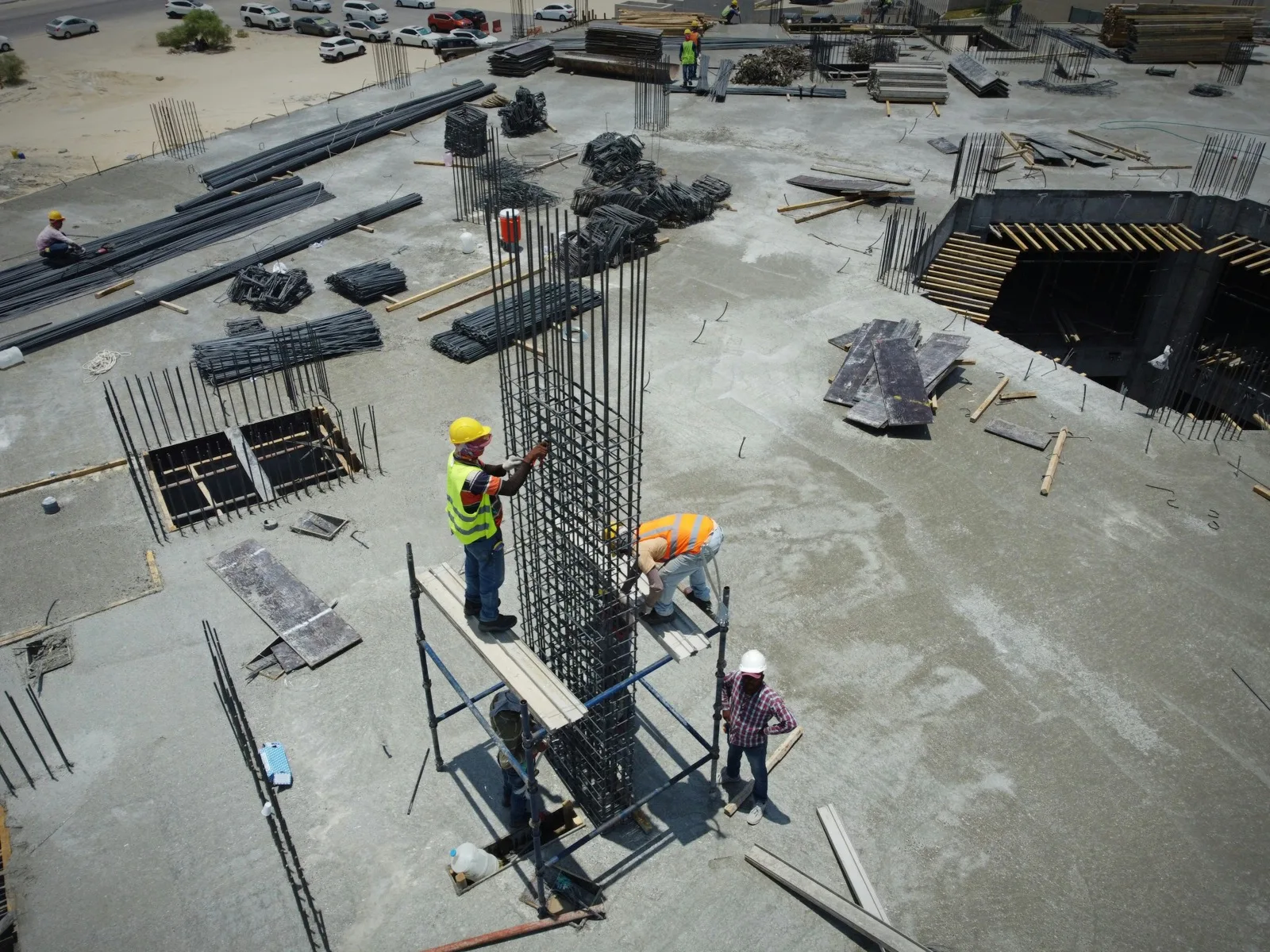 Two workers at a foundation column with rebar, seen from above