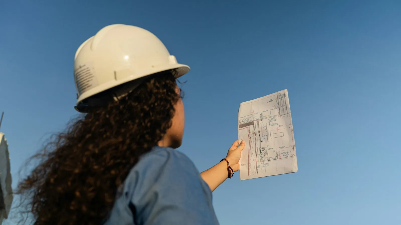 Field engineer holding a drawing up against a blue sky