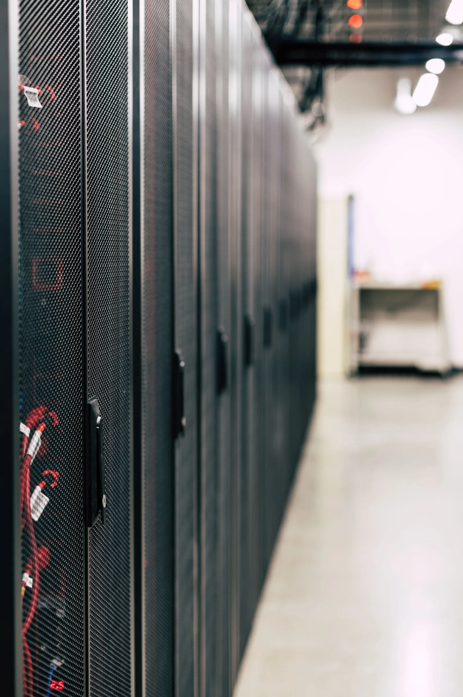Row of server cabinets in a data hall, lit aisle at the far end