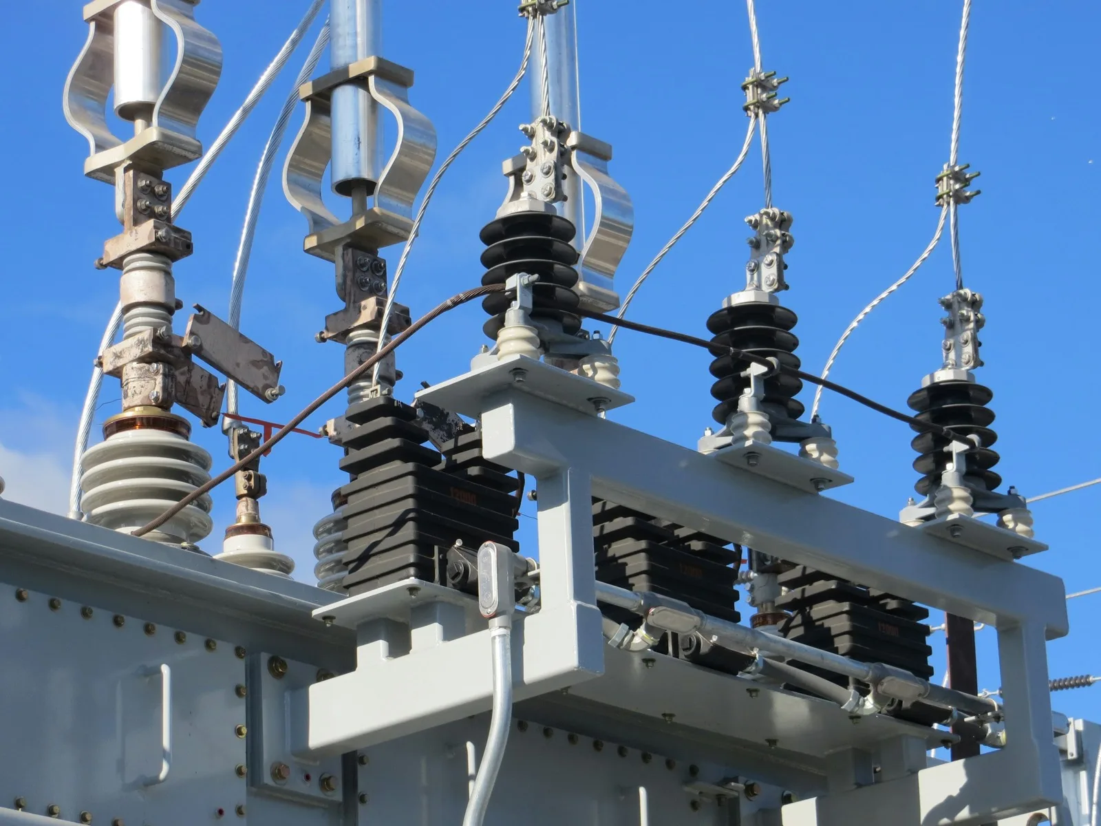 Transformer bushings and surge arresters under a blue sky