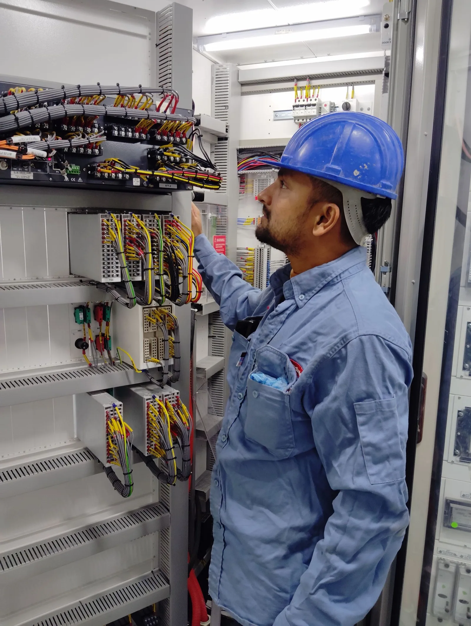 Electrician checking wiring inside a control cabinet