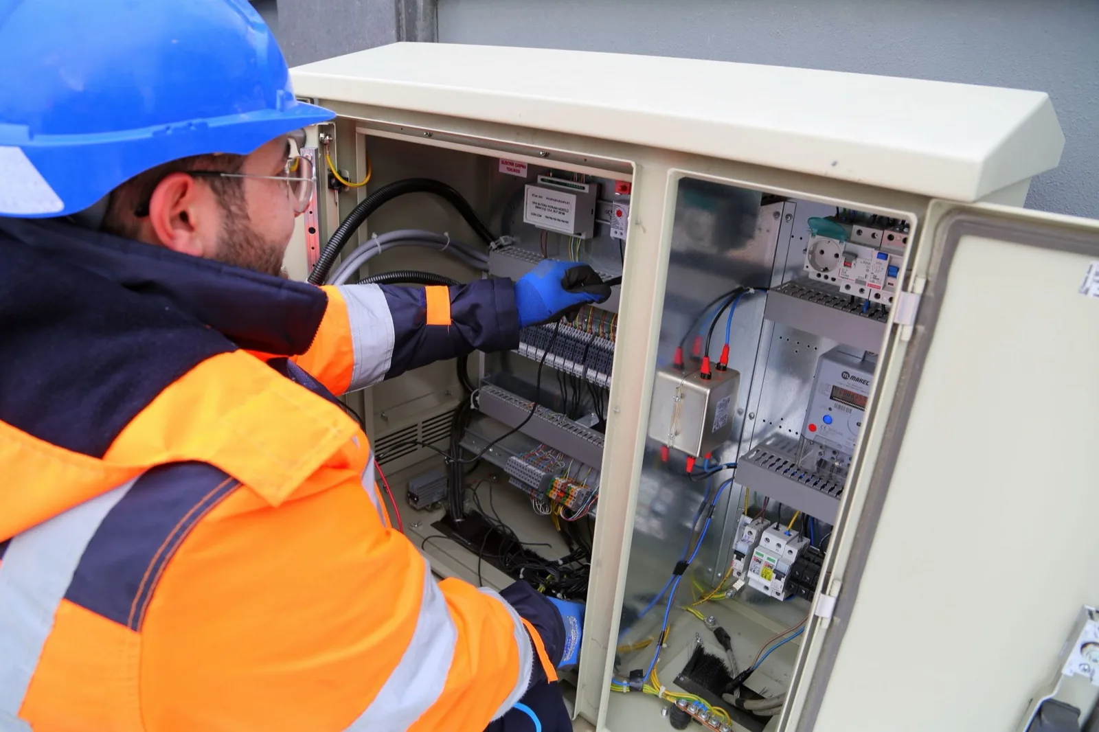 Engineer in a safety vest working in an outdoor electrical cabinet